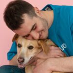 Smiling man warmly embraces his dog, creating a heartwarming studio portrait.